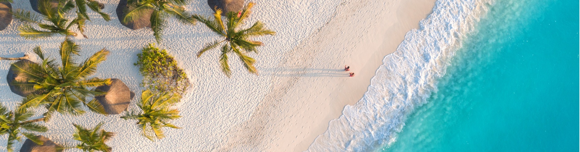 aerial-view-of-umbrellas-palms-on-the-sandy-beach-of-indian-ocean-at-sunset-summer-holiday-in 1900x500