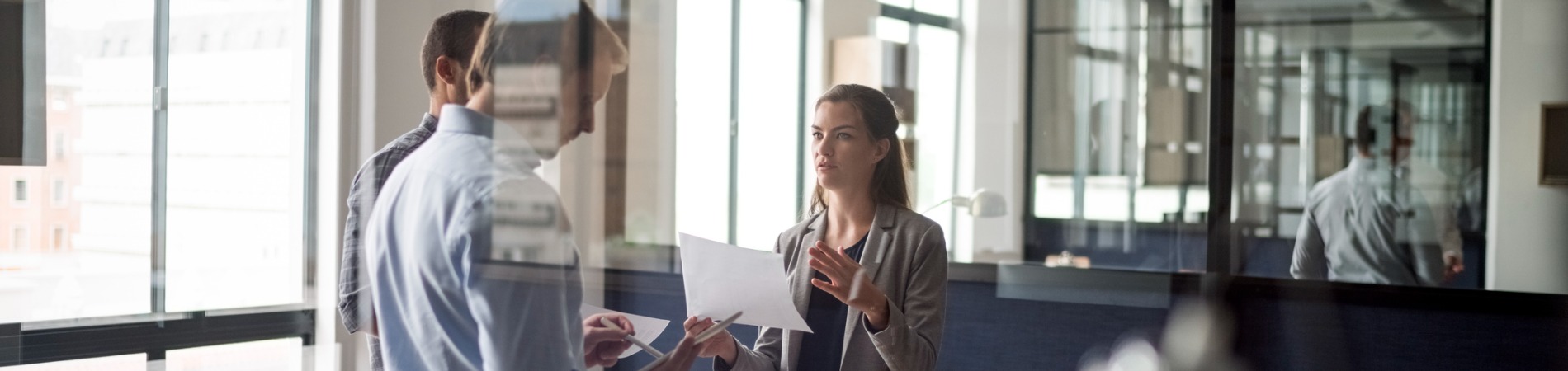 businesswoman-talking-to-colleague-in-office 1900 x 500