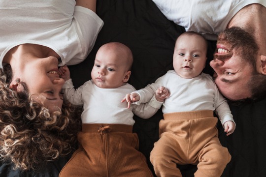 happy-parents-lying-in-bed-with-their-twin-baby-boys-and-smiling-540x360